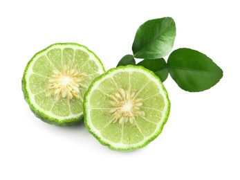 Halves of fresh ripe bergamot fruit and green leaves on white background