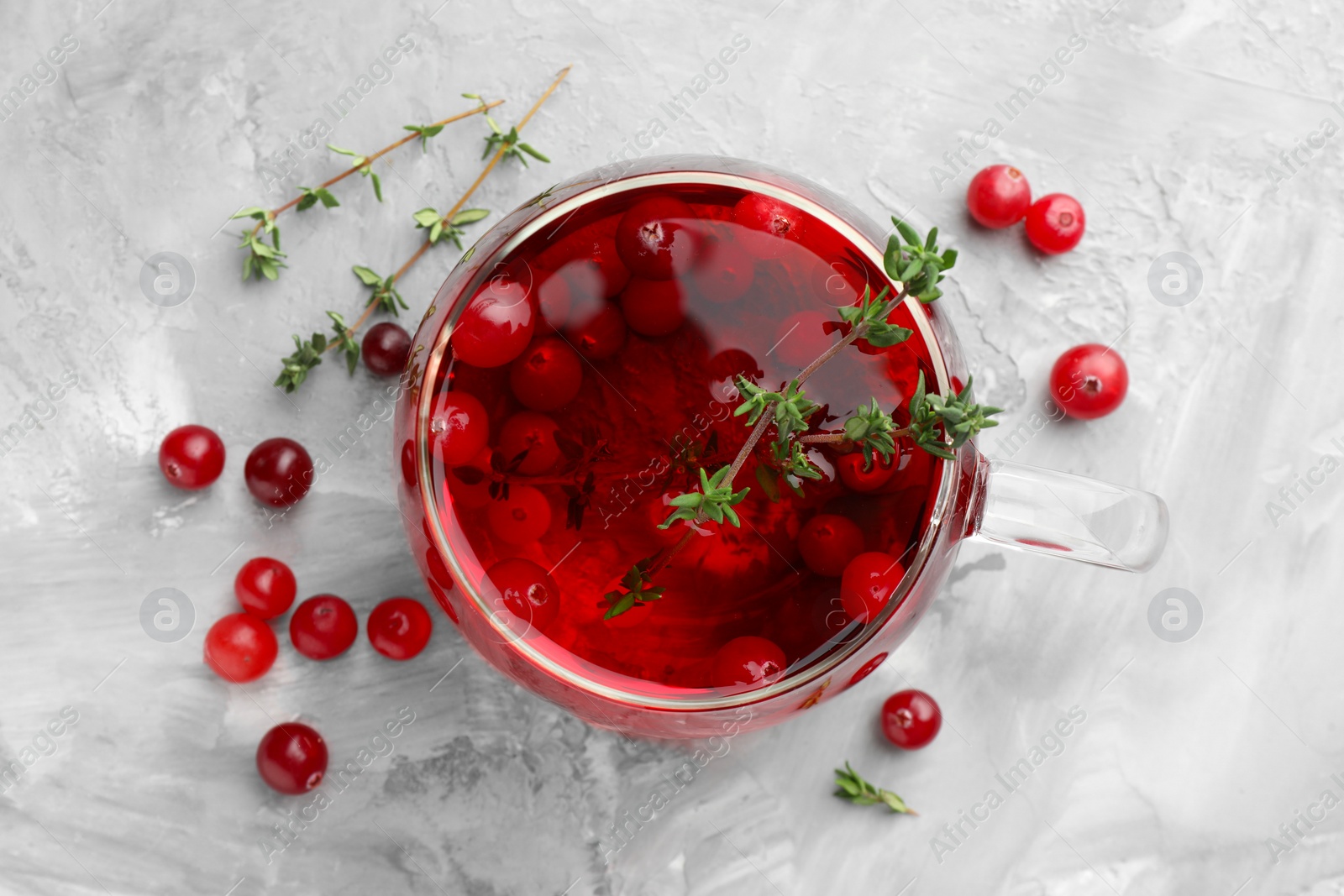 Photo of Delicious cranberry tea with thyme and berries on grey table, flat lay