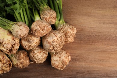 Photo of Fresh raw celery roots on wooden table, flat lay. Space for text