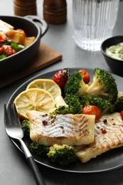 Photo of Tasty cod cooked with vegetables served on grey table