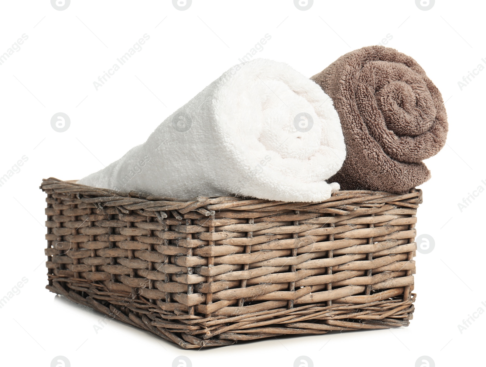 Photo of Rolled soft terry towels in wicker basket on white background