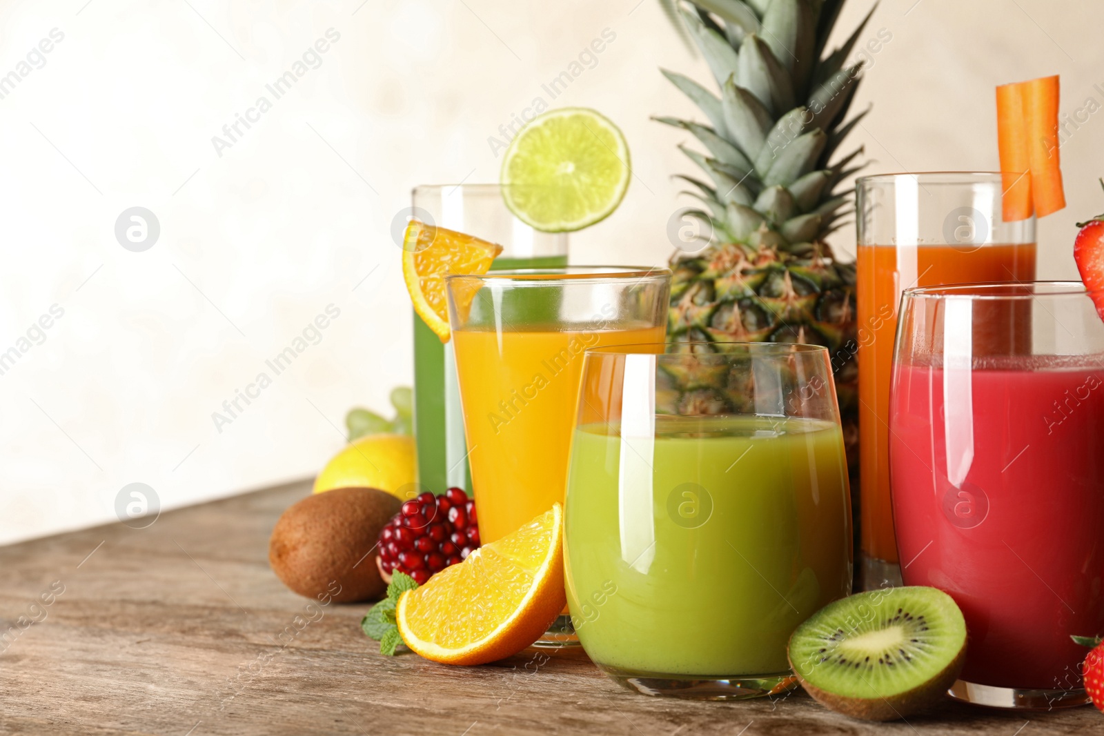 Photo of Glasses with different juices and fresh fruits on table. Space for text