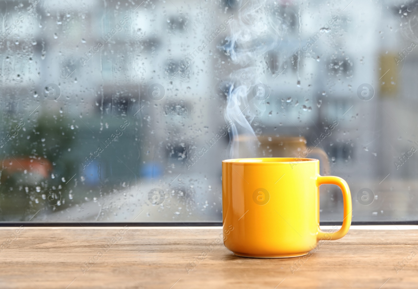 Photo of Cup of hot drink near window on rainy day. Space for text