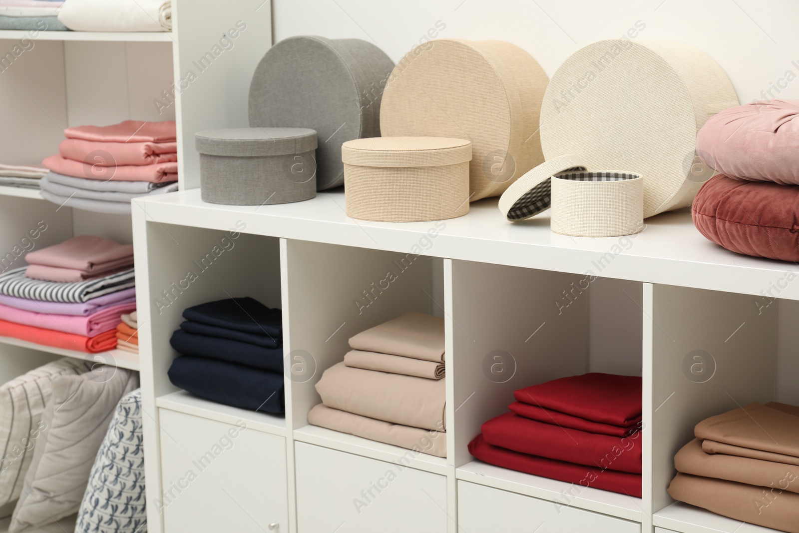 Photo of Different colorful bed linens and decorative boxes on display in home textiles store