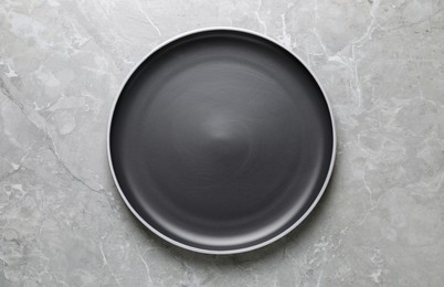 Photo of New dark plate on light grey marble table, top view
