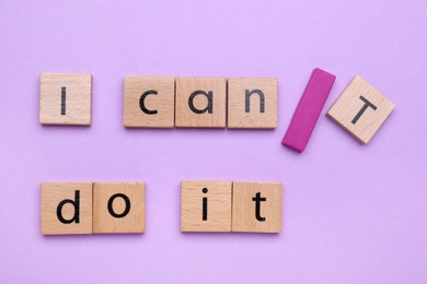Photo of Motivation concept. Changing phrase from I Can't Do It into I Can Do It by adding slash symbol on violet background, flat lay