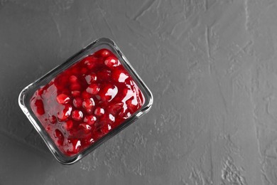 Photo of Fresh cranberry sauce in glass bowl on gray textured table, top view. Space for text