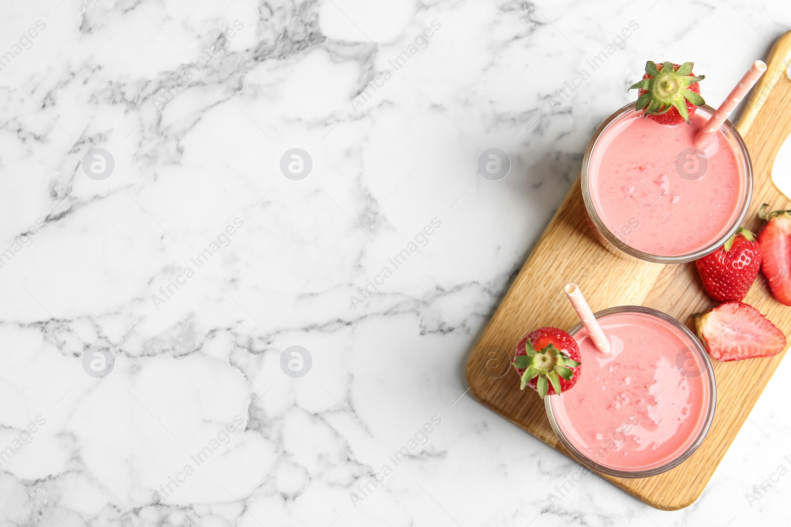 Photo of Tasty strawberry smoothies in glasses on white marble table, top view. Space for text