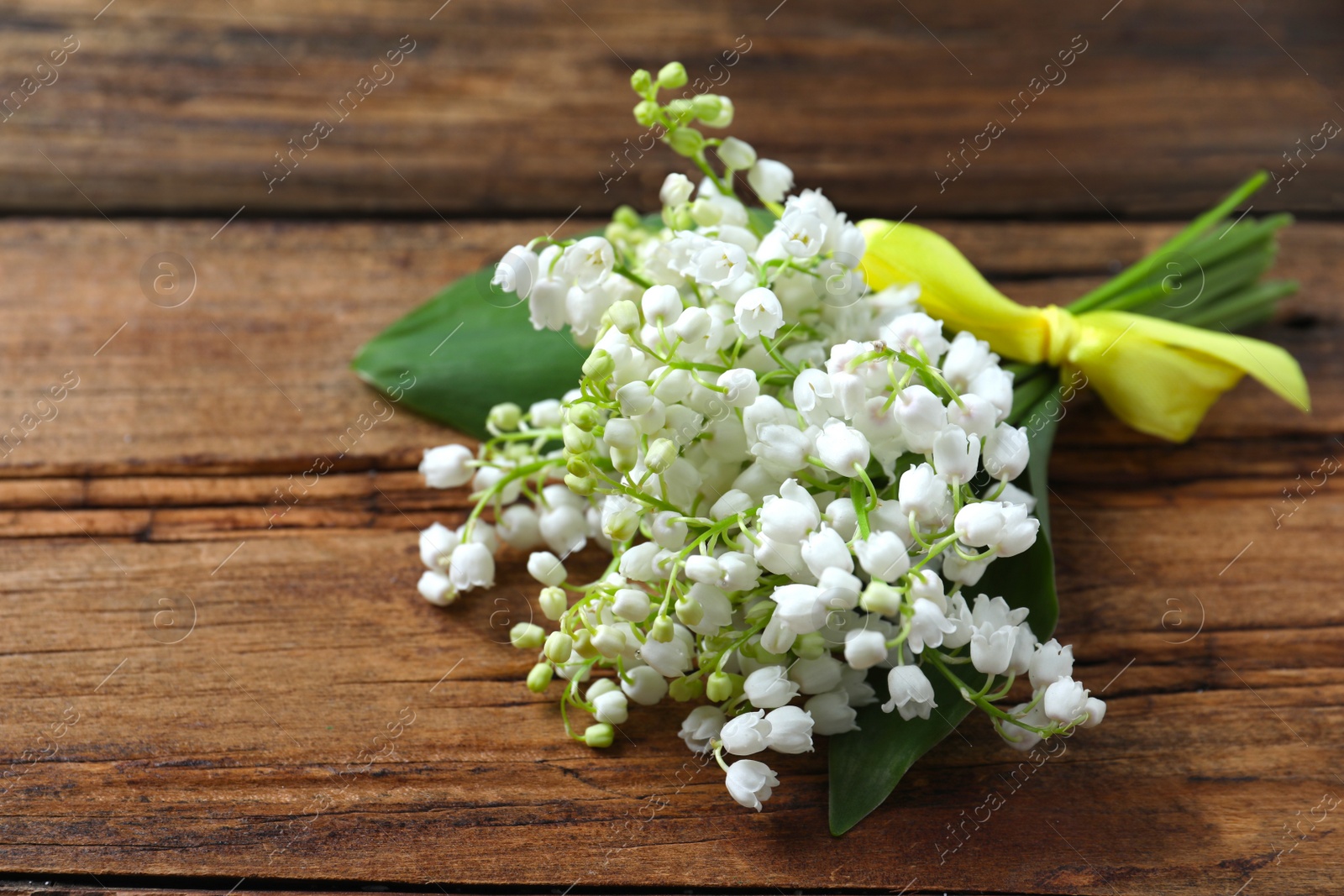 Photo of Beautiful lily of the valley flowers on wooden table