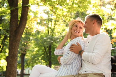 Photo of Happy couple sitting on bench in summer park