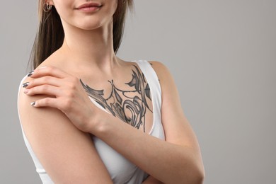 Woman with cool tattoos on grey background, closeup