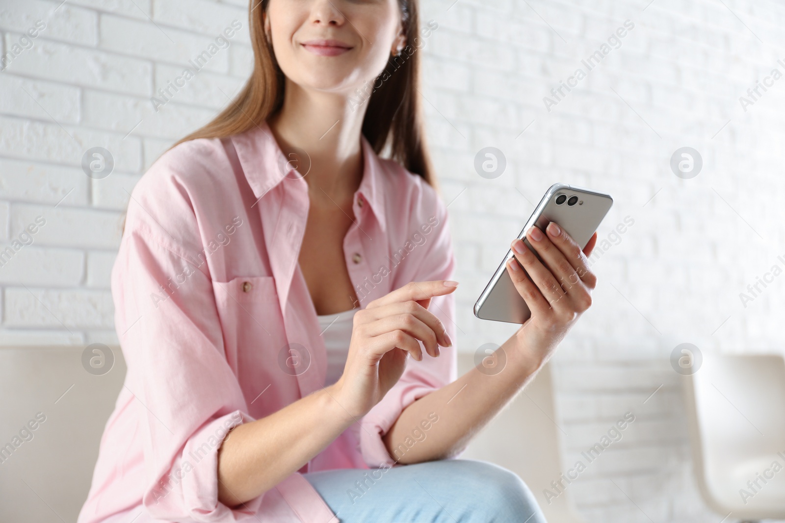 Photo of Young woman using modern smartphone indoors, closeup