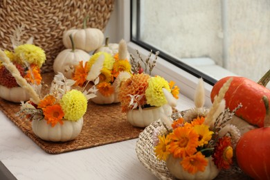 Composition with small pumpkins, beautiful flowers and spikelets on white wooden window sill indoors