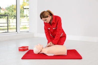 Woman in uniform practicing first aid on mannequin indoors