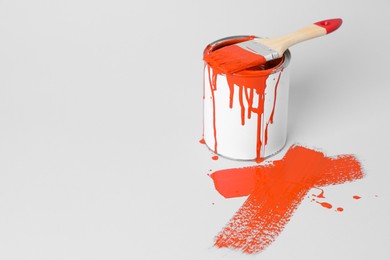 Photo of Can of orange paint and brush on white background. Space for text