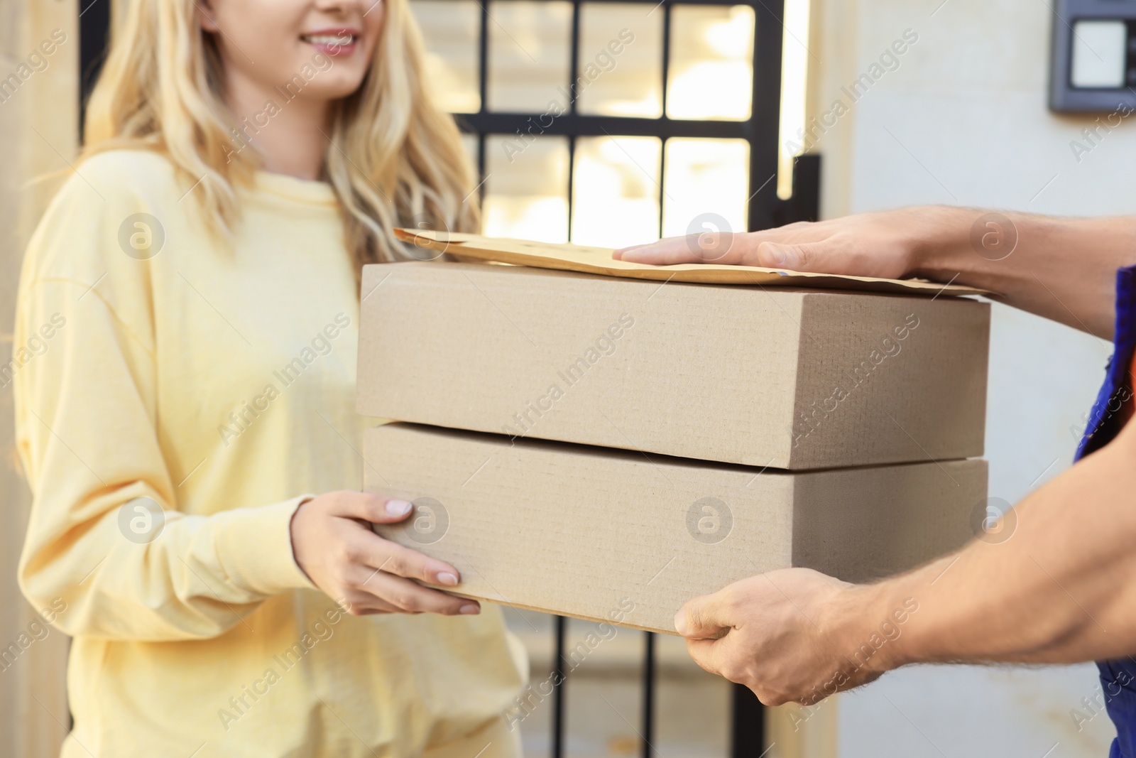 Photo of Woman receiving parcels from courier outdoors, closeup