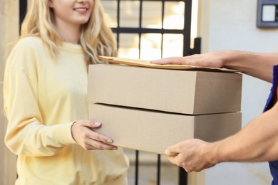Woman receiving parcels from courier outdoors, closeup