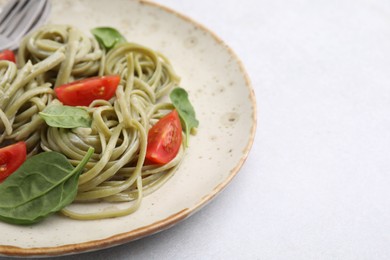 Photo of Tasty pasta with spinach and tomatoes on light table, closeup. Space for text