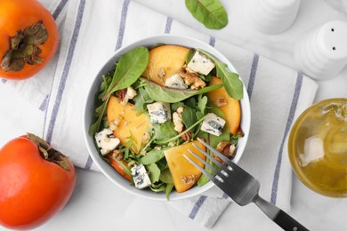 Photo of Tasty salad with persimmon, blue cheese and walnuts served on white table, flat lay
