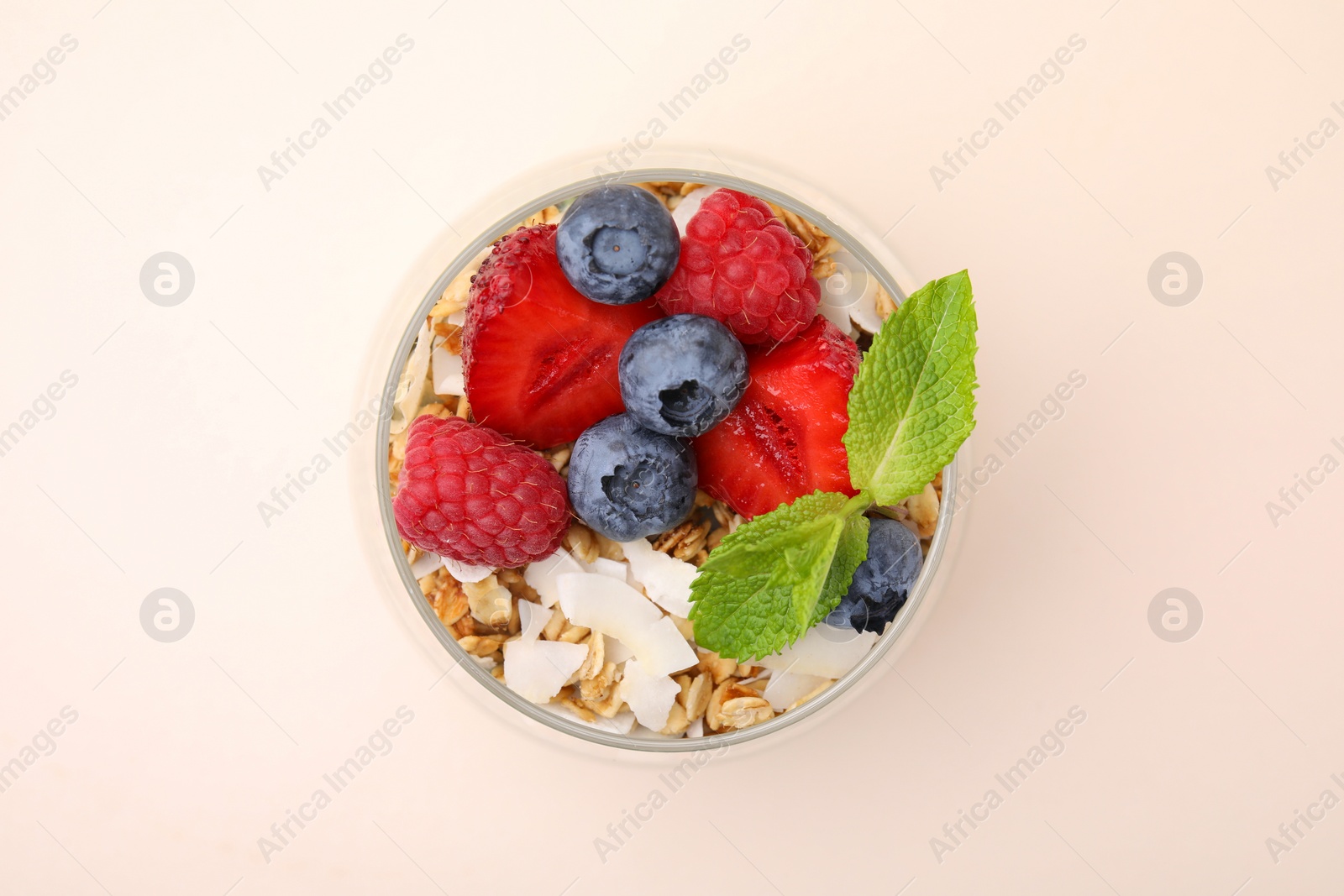 Photo of Tasty oatmeal with berries and mint on beige background, top view. Healthy breakfast