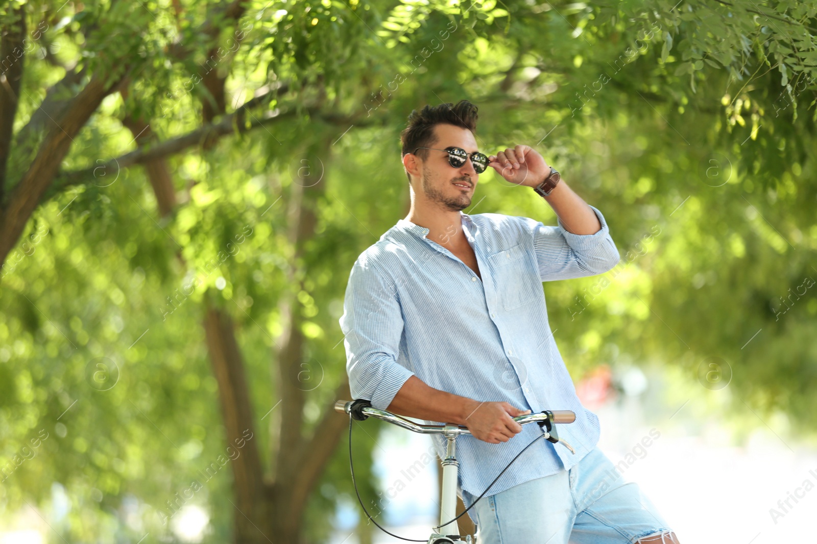 Photo of Handsome young hipster man with bicycle in park