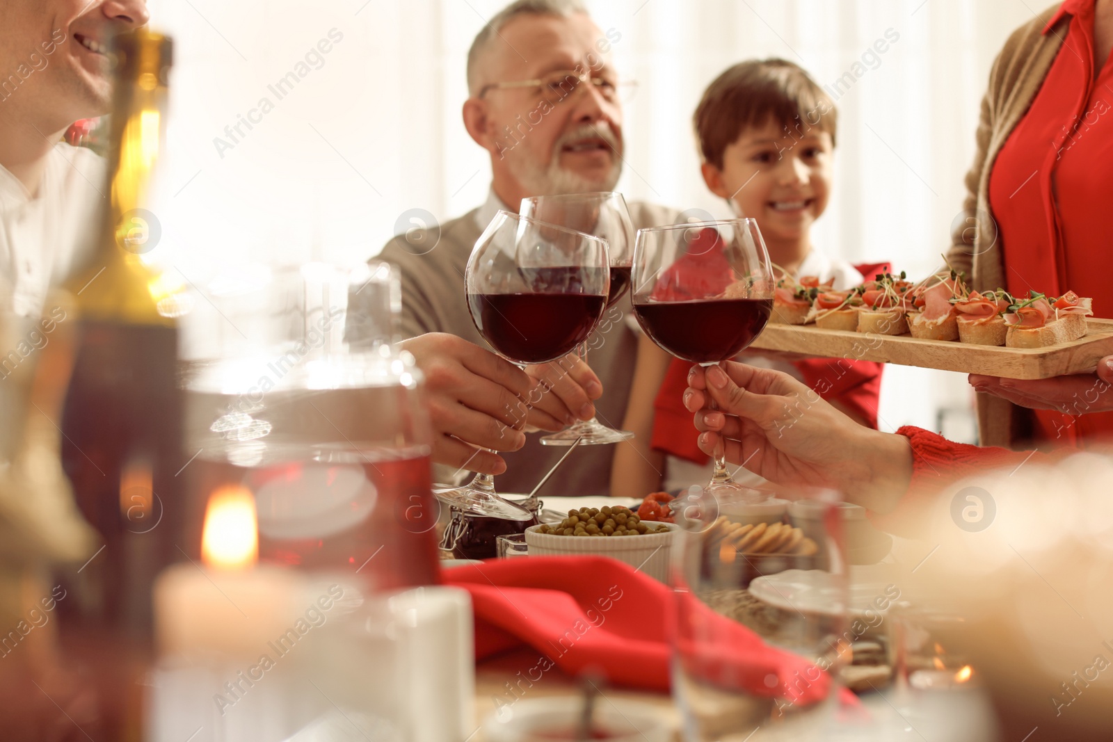 Photo of Family clinking glasses of wine at festive dinner, focus on hands. Christmas celebration