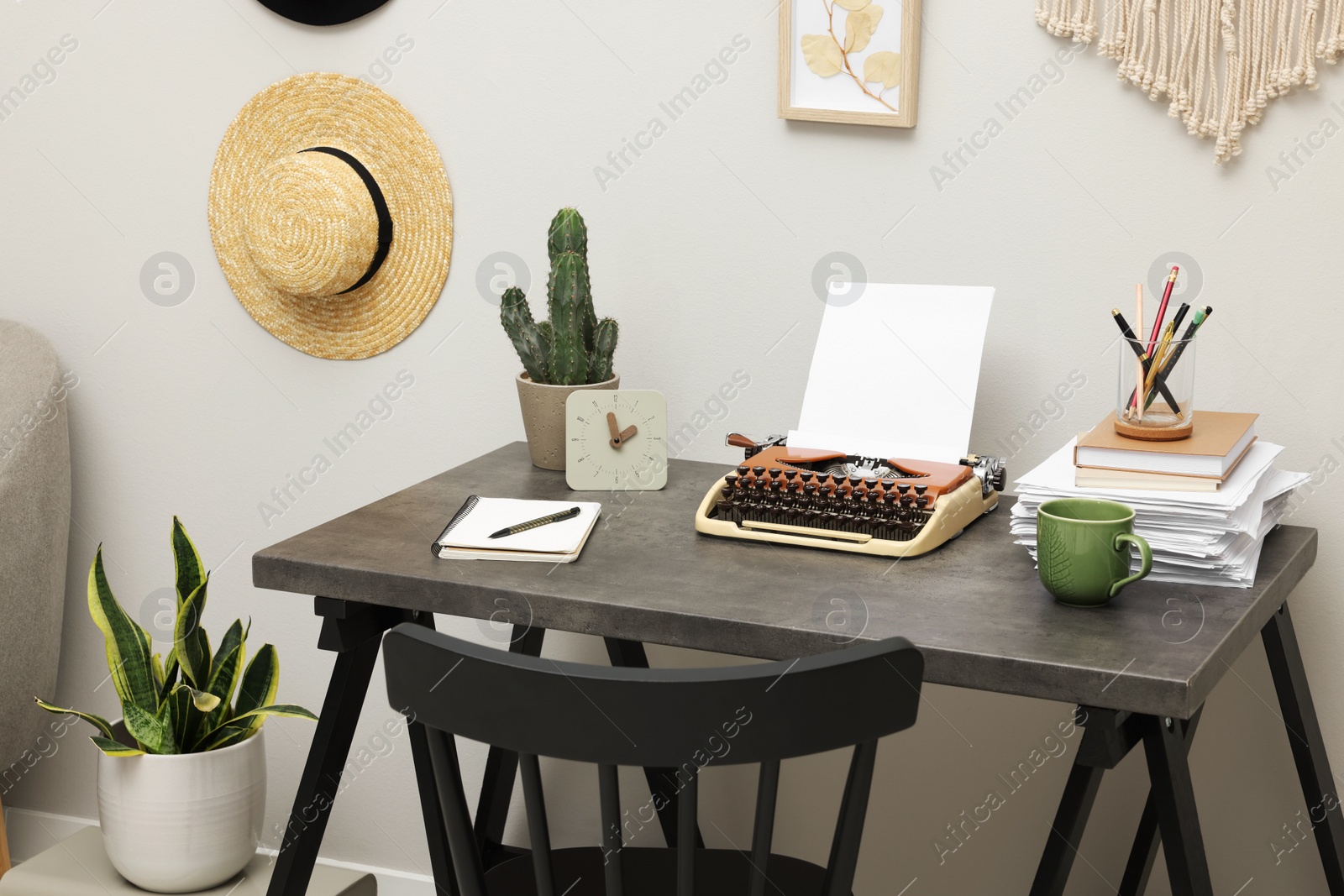 Photo of Typewriter and stack of papers on dark table in room. Writer's workplace