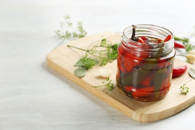 Photo of Glass jar of pickled chili peppers and ingredients on white table. Space for text