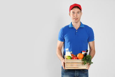 Photo of Courier with fresh products on light background, space for text. Food delivery service