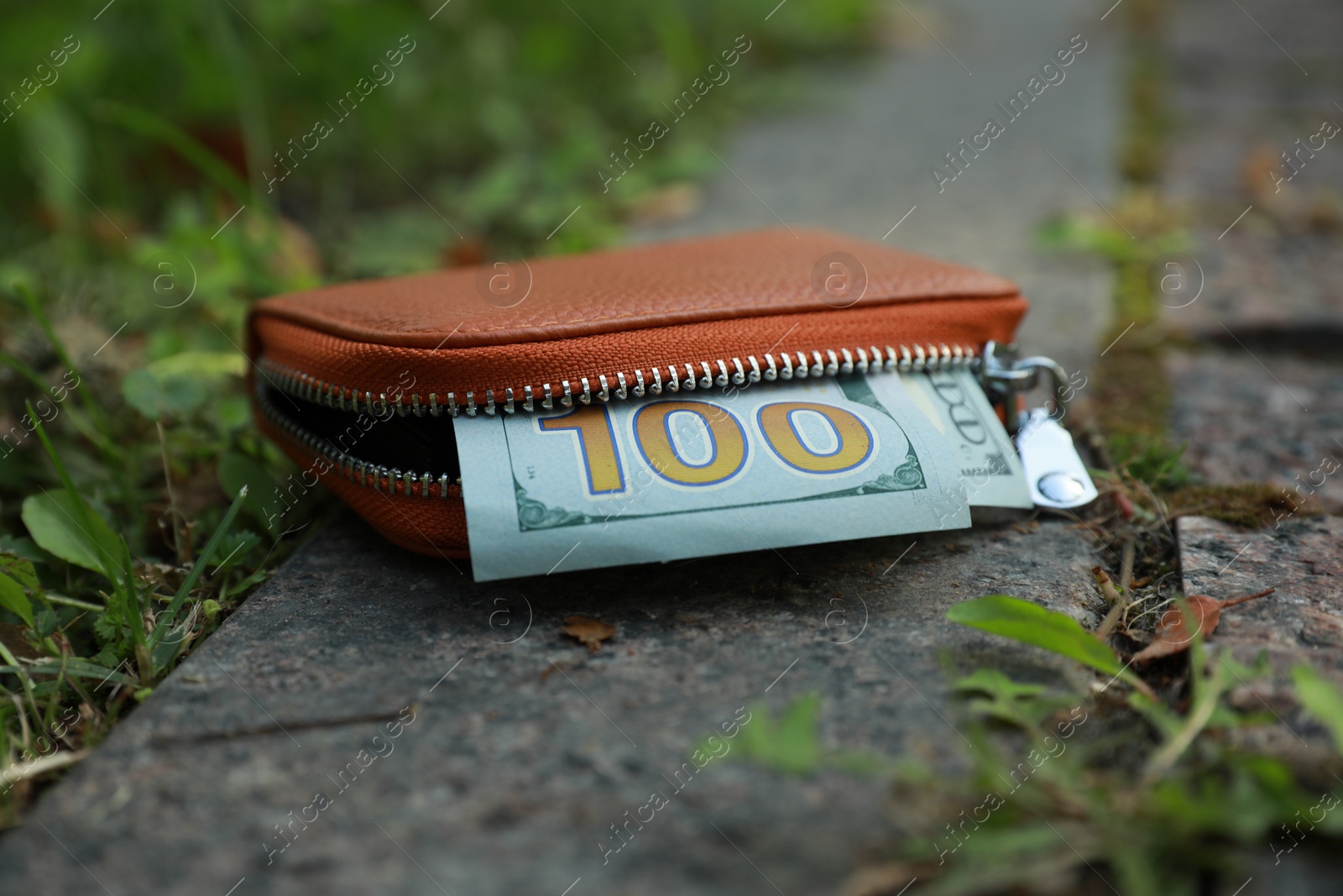 Photo of Brown leather purse on pavement outdoors, closeup. Lost and found