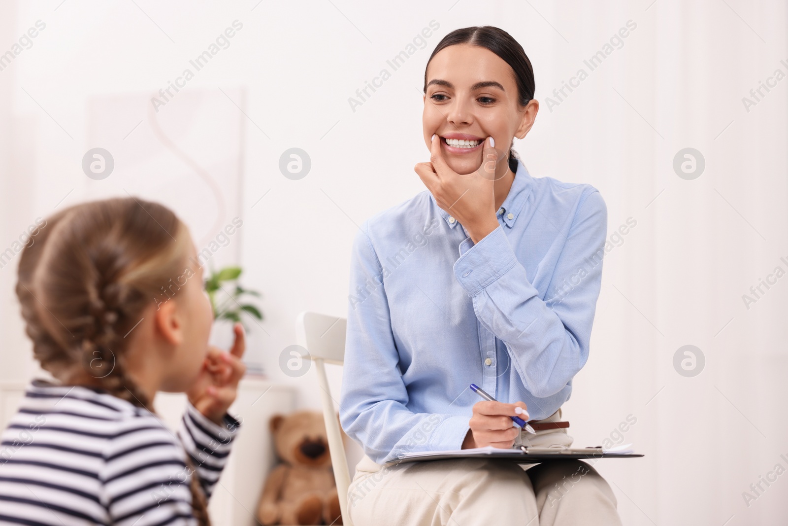 Photo of Dyslexia treatment. Speech therapist working with girl in room