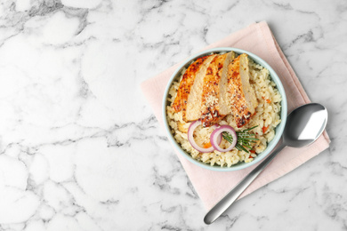 Photo of Delicious chicken risotto served on white marble table, flat lay. Space for text