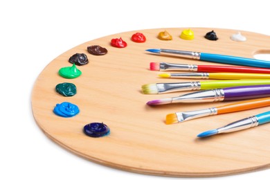 Photo of Palette with paints and brushes on white background, closeup. Artist equipment