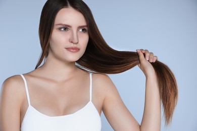 Photo of Young woman with strong healthy hair on light blue background