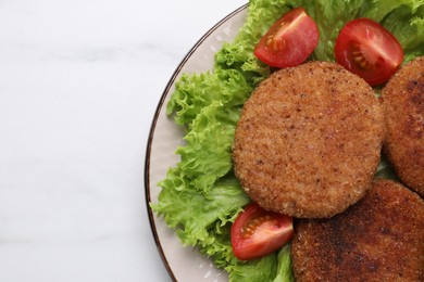 Plate with delicious vegan cutlets, lettuce and tomatoes on white marble table, top view. Space for text