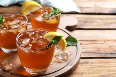 Photo of Delicious iced tea on wooden table. Space for text