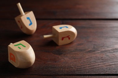 Photo of Hanukkah traditional dreidel with letters Pe and He on wooden table. Space for text