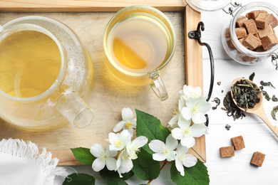 Photo of Flat lay composition with tea and fresh jasmine flowers on white wooden table