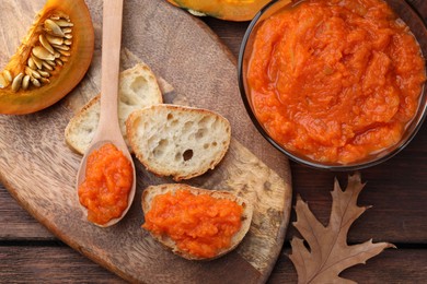 Photo of Slices of bread with delicious pumpkin jam and fresh pumpkin on wooden table