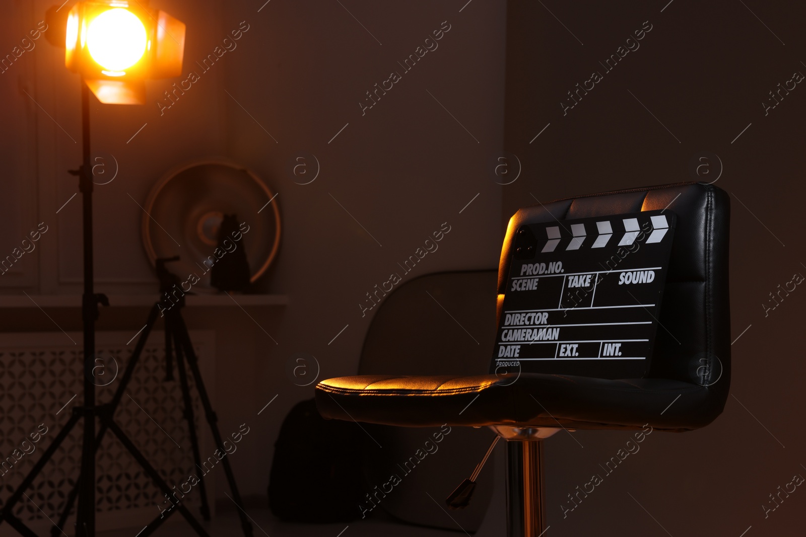 Photo of Casting call. Chair, clapperboard and different equipment in modern studio, space for text