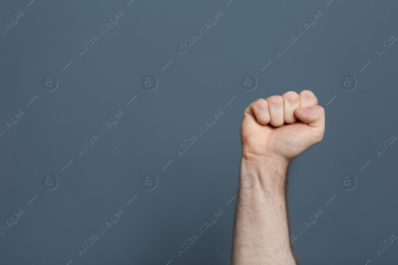 Photo of Young man showing clenched fist on color background. Space for text