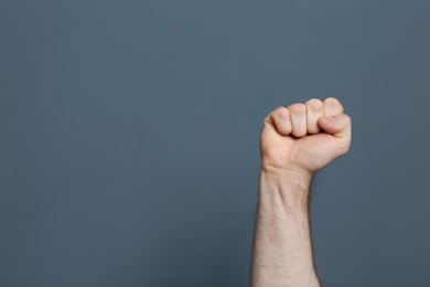 Young man showing clenched fist on color background. Space for text