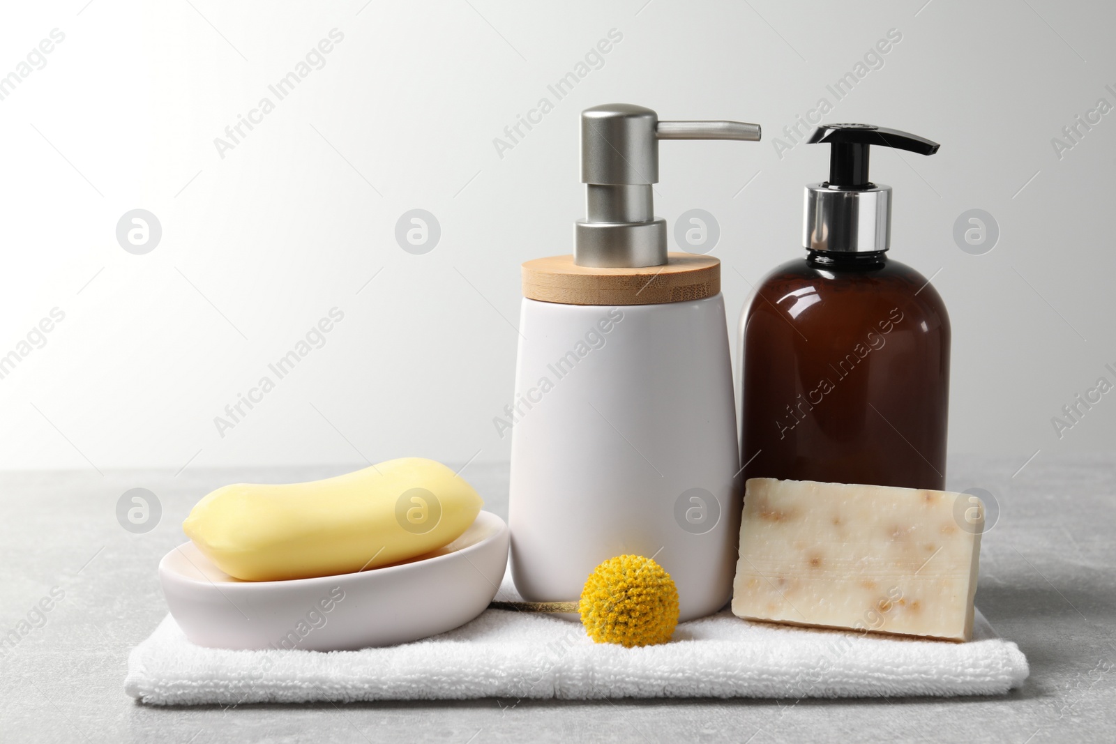 Photo of Soap bars, dispensers and terry towel on light grey table