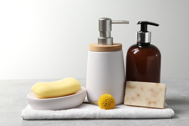 Photo of Soap bars, dispensers and terry towel on light grey table