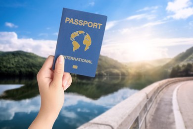 Image of Woman holding international passport and beautiful view of road along lake on background