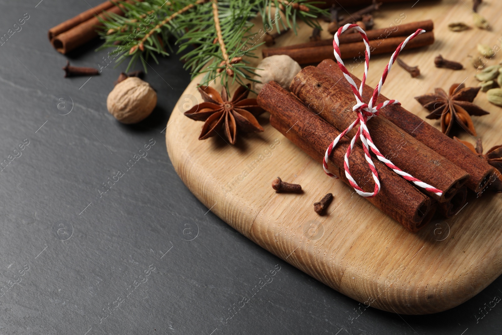 Photo of Different spices, nuts and fir branches on gray table, space for text