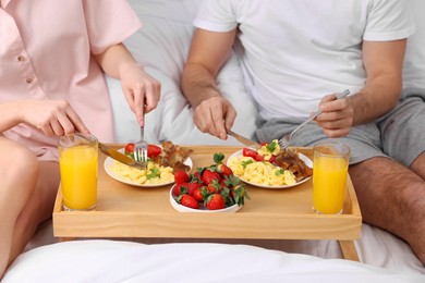 Photo of Couple eating tasty breakfast on bed, closeup