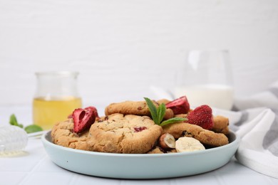 Photo of Cookies with freeze dried fruits, mint and nuts on white tiled table, closeup. Space for text