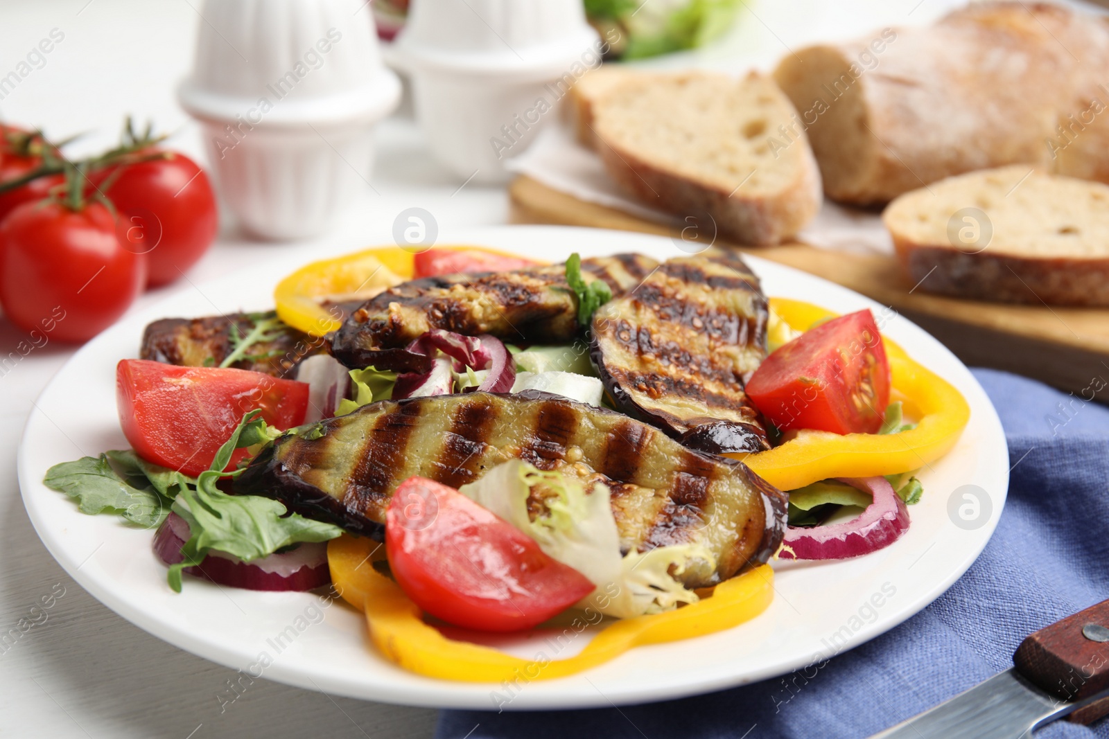 Photo of Delicious salad with roasted eggplant served on table, closeup