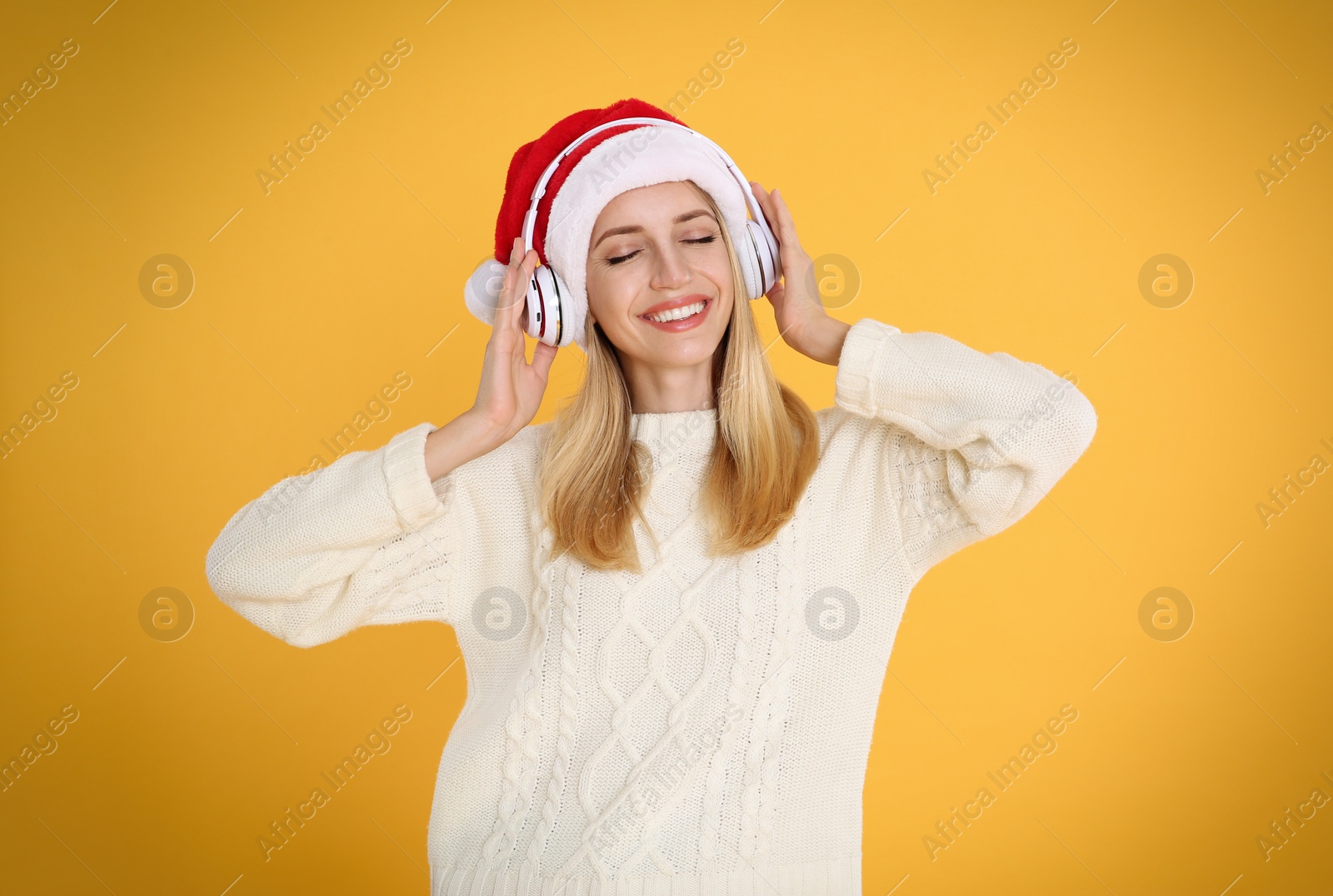 Photo of Happy woman with headphones on yellow background. Christmas music